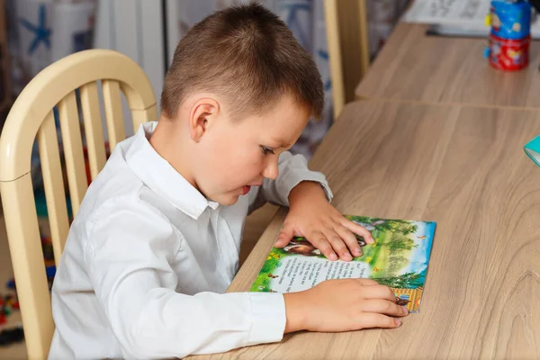 Ragazzo Con Una Camicia Bianca Siede Tavolo Legge Libro Casa — Foto Stock