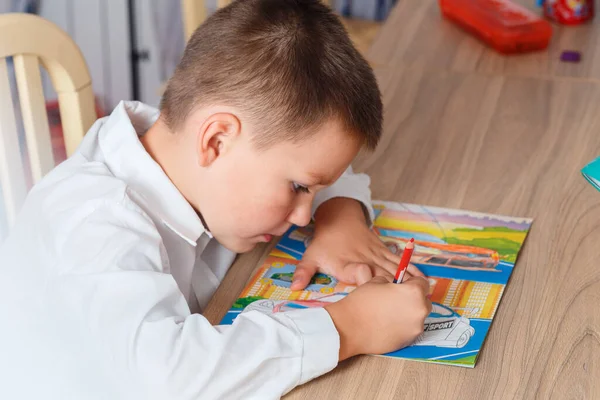 Семирічний Хлопчик Білій Сорочці Старанно Малює Машини Сидять Своїм Столом — стокове фото