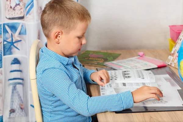 Ένα Οκτάχρονο Αγόρι Κάθεται Ένα Γραφείο Στο Σπίτι Και Διαβάζει — Φωτογραφία Αρχείου