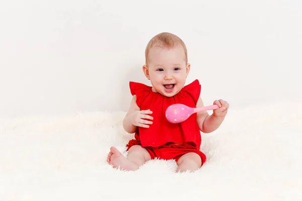 Una Niña Sonriente Ocho Meses Con Traje Rojo Sostiene Sonajero —  Fotos de Stock