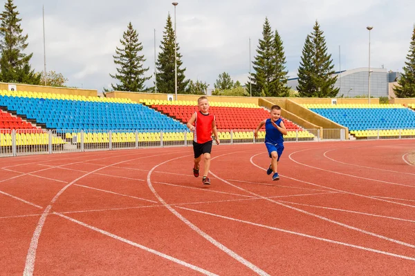 children run through the sports stadium.two athletic children in sports uniforms
