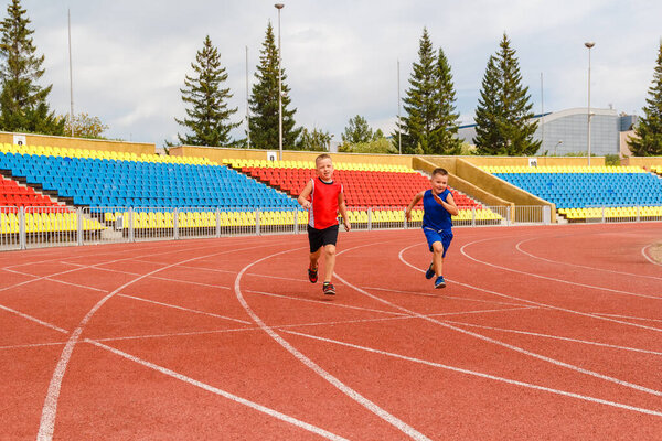 дети бегают по спортивному стадиону. Двое атлетичных детей в спортивной форме
