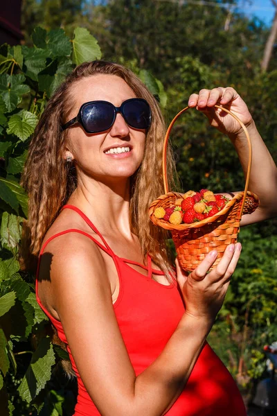 smiling pregnant woman and basket of berries.