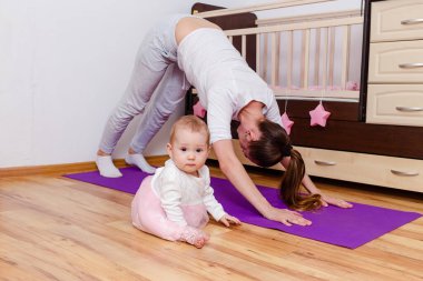 Evde kal. Bir kadın çocuğuyla birlikte evde yoga yapıyor. Anne ve çocuk.