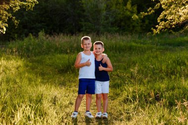 Yazın şortlu ve uzun tişörtlü iki çocuk.