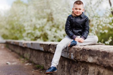 Deri ceketli, açık havada 7 yaşında bir çocuk.