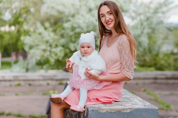 ベビーガールでピンクのドレス膝の上に座る笑顔母屋外 — ストック写真
