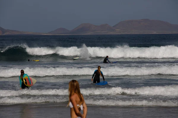 Surfers and kiters at sea on surf beach Famara — Stock Photo, Image