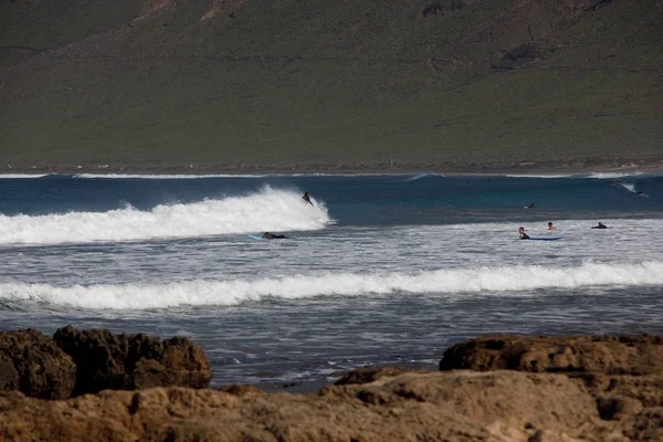 Surfers and kiters at sea on surf beach Famara — Stock Photo, Image