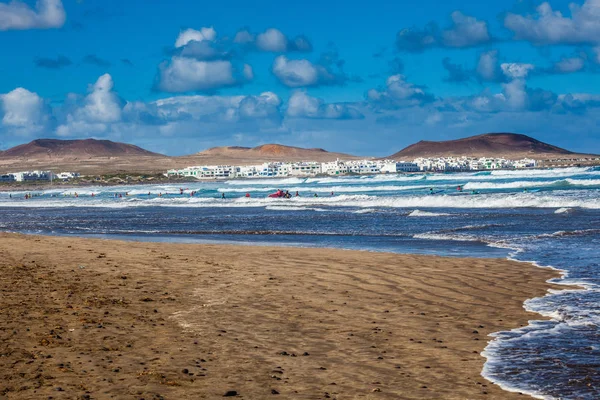Surfistas y kiters en el mar en la playa de surf Famara en Lanzarote —  Fotos de Stock