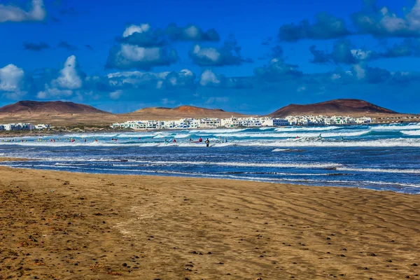 Surfistas y kiters en el agua en la playa de Famara, Lanzarote — Foto de Stock