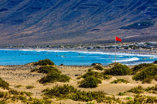 Surfare stranden Famara på Lanzarote har alltid en röd flagga. — Stockfoto