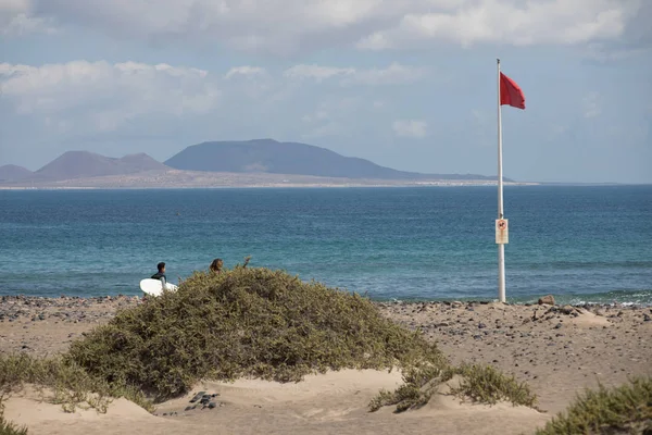 La bandera roja pesa en el viento en Surfers Beach Famara en Lanza —  Fotos de Stock