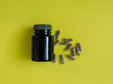 Tıbbi kapsüller sarı arka plana saçılmış..