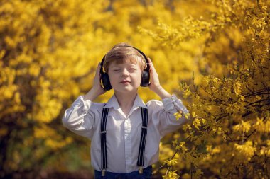 Bir bahar günü, kulaklıklı bir çocuk gözleri kapalı müzik dinler..