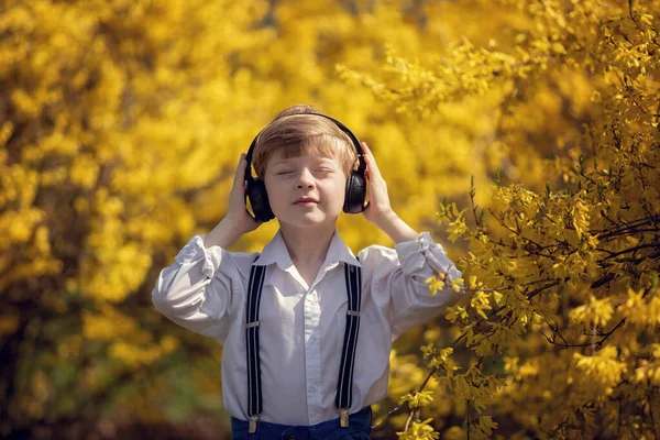 Bir bahar günü, kulaklıklı bir çocuk gözleri kapalı müzik dinler..