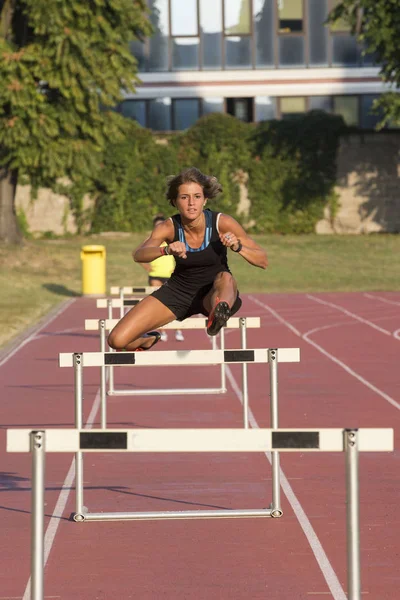 女性の陸上競技で障害物をジャンプ — ストック写真