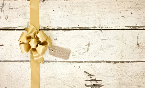 Gold Christmas bow on rosy white distressed wood background — Stock Photo, Image