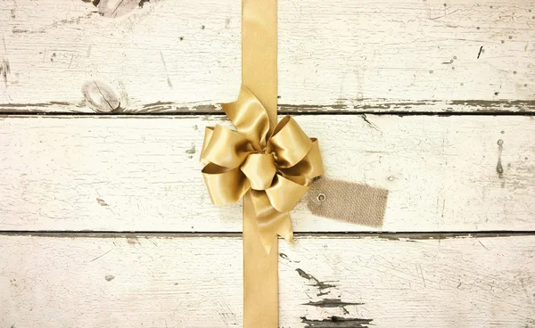 Gold Christmas bow on rosy white distressed wood background — Stock Photo, Image