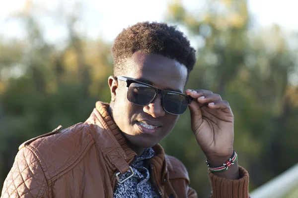 Bonito jovem negro em óculos de sol e uma jaqueta de couro em um — Fotografia de Stock