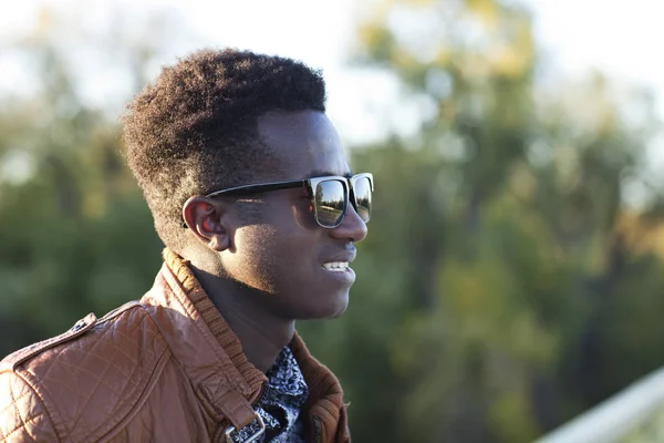 Bonito jovem negro em óculos de sol e uma jaqueta de couro em um — Fotografia de Stock