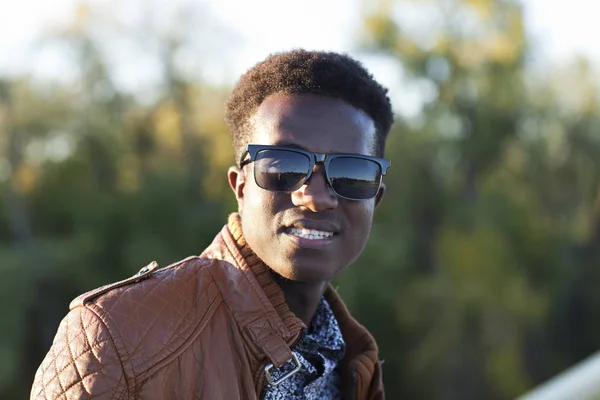 Bonito jovem negro em óculos de sol e uma jaqueta de couro em um — Fotografia de Stock
