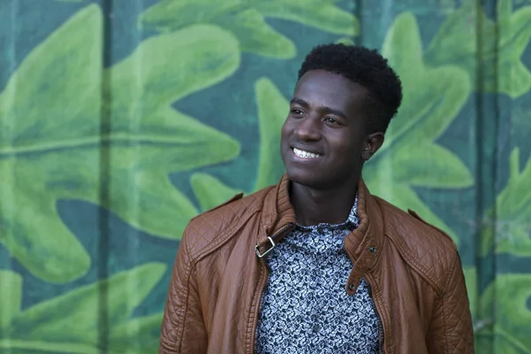 Bonito jovem negro sorri na frente da parede pintada — Fotografia de Stock