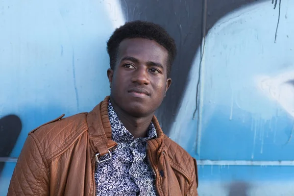 Bonito jovem negro na frente da superfície de metal pintado — Fotografia de Stock