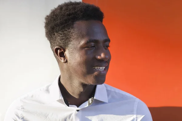 Bonito jovem negro sorrindo na frente de laranja e branco di — Fotografia de Stock