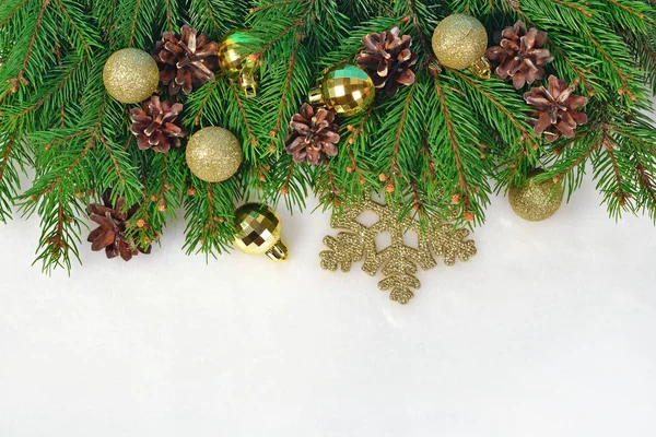 Golden Christmas decorations and spruce branch and cones on a wh — Stock Photo, Image