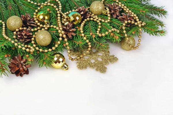 Golden Christmas decorations and spruce branch and cones on a wh Stock Photo