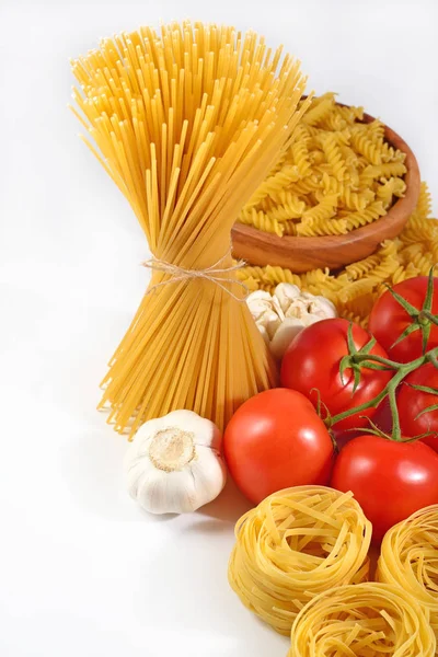 Pişmemiş İtalyan makarna, olgun domates dalı ve sarımsak bir whi