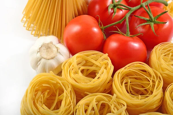 Pastas italianas crudas, rama de tomates maduros y ajo — Foto de Stock