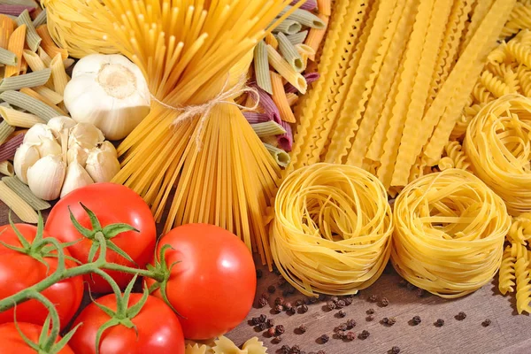 Pastas italianas sin cocer, rama de tomates maduros, ajo y negro p — Foto de Stock