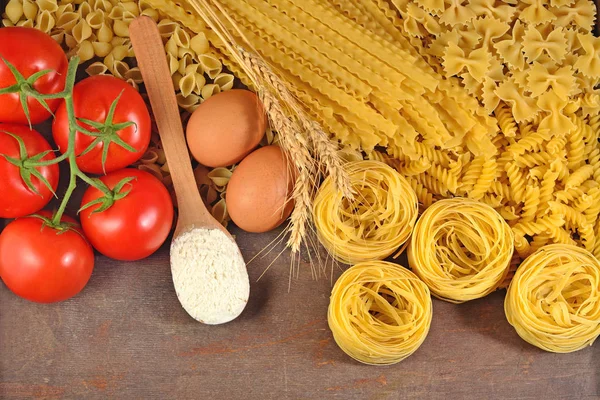 Pastas italianas sin cocer, rama de tomates maduros, harina y huevos — Foto de Stock