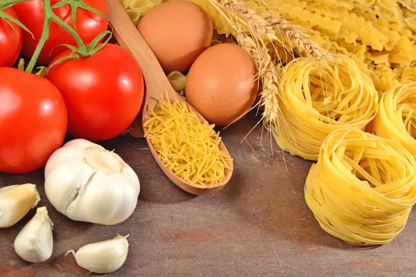Pastas italianas sin cocer, rama de tomates maduros, ajo y huevos — Foto de Stock