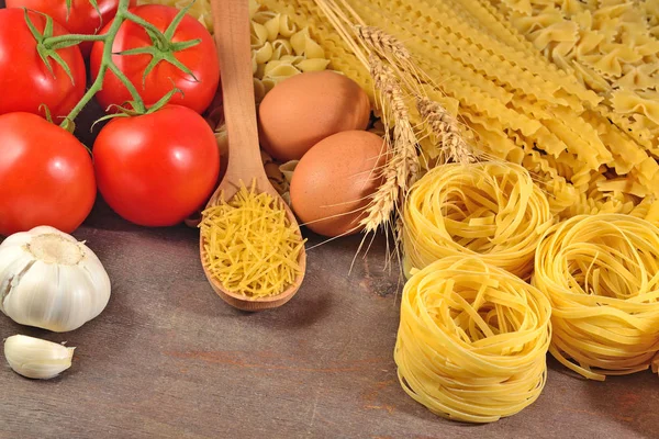 Pastas italianas sin cocer, rama de tomates maduros, ajo y huevos — Foto de Stock