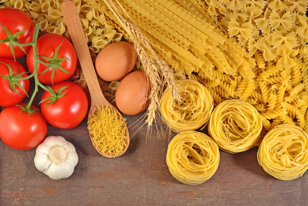 Pastas italianas sin cocer, rama de tomates maduros, ajo y huevos — Foto de Stock