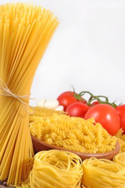 Pişmemiş makarna çeşitleri ve beyaz bir dalda olgun domates