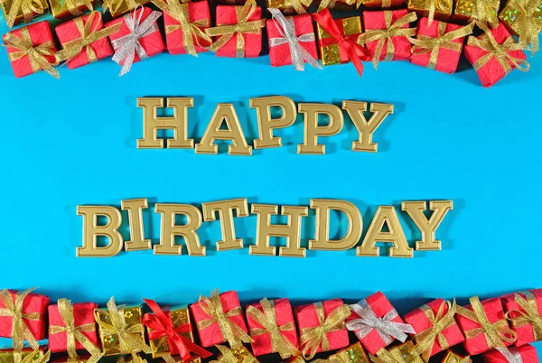 Happy birthday golden text and golden and red gifts on a blue — Stock Photo, Image