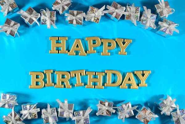 Happy birthday golden text and silver gifts on a blue — Stock Photo, Image