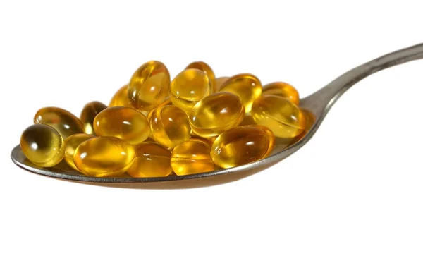 Omega-3 fish fat oil capsules in spoon on a white