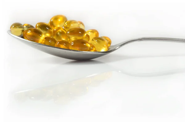 Омега-3 жирні таблетки з риб'ячого жиру в ложці на білому — стокове фото