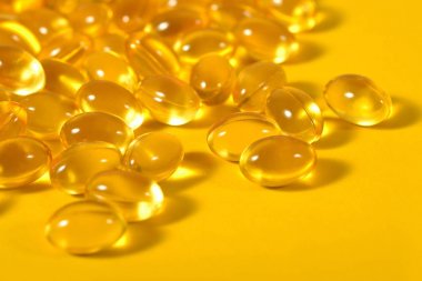Omega-3 balık yağı kapsülleri sarı bir arka plan üzerinde yakın çekim şişman.