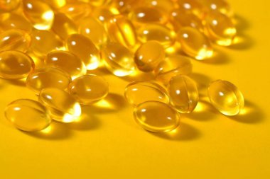 Omega-3 balık yağı kapsülleri sarı bir arka plan üzerinde yakın çekim şişman.