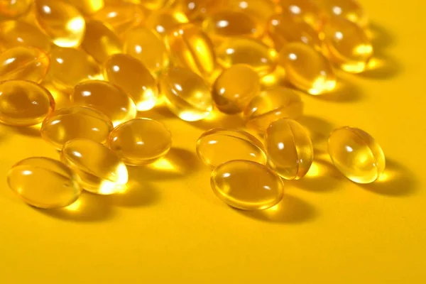 Omega-3 rybí tuk olej kapsle zblízka na žlutém podkladu. — Stock fotografie