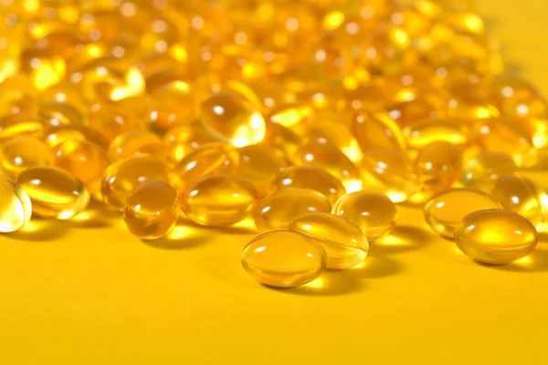 Omega-3 rybí tuk olej kapsle zblízka na žlutém podkladu. — Stock fotografie