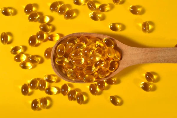 Omega-3 rybí tuk olej kapsle v vařečku na žluté — Stock fotografie