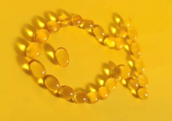 Omega-3 fish fat oil capsules shaped in fish on a yellow — Stock Photo, Image