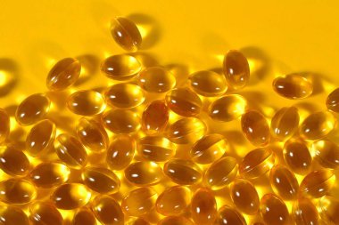 Omega-3 balık yağı kapsülleri sarı bir arka plan üzerinde şişman